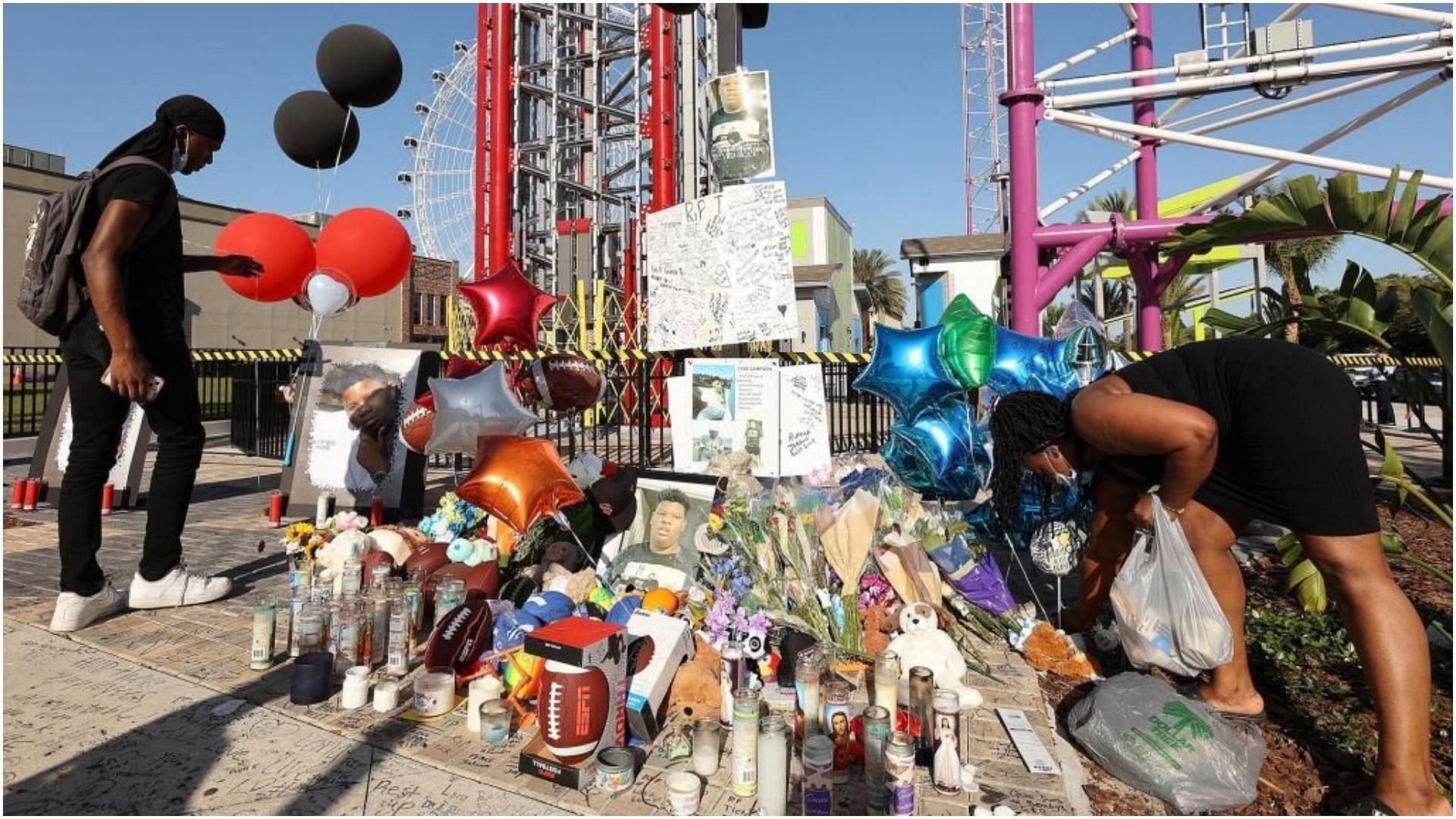 Family members and friends of Tyre Sampson leave flowers and other items at a vigil in front of the Orlando Free Fall drop tower (Image via Getty Images/Stephen M. Dowell)